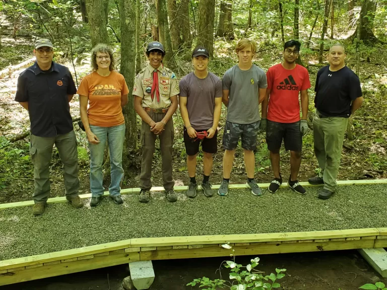 Boy Scout Ashwath Sridhar and volunteers stand on the completed bridge.